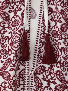 Nahaufnahme des Paisley-Musters mit weinroten Quasten und weißem V-Ausschnitt-Detail