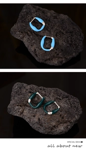 Detailed macro view of S925 silver earrings with blue and green enamel on volcanic rock