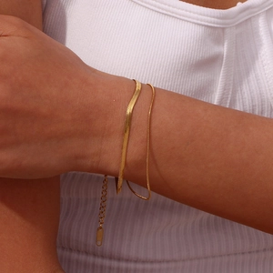 Detail of layered gold snake chain bracelet with adjustable clasp on a model's wrist
