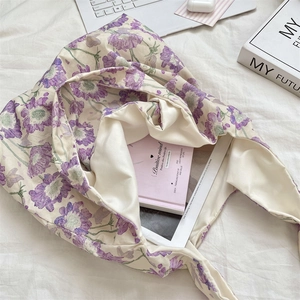 Detail of floral canvas tote bag showing purple flower print and large capacity interior