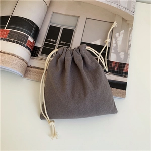 Minimalist grey drawstring storage bag in cotton linen fabric on a magazine background