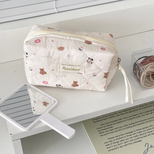 Detailed view of quilted donut bear makeup bag with brand tag and ribbon zipper pull