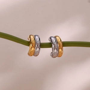 Macro detail of curved two-tone double layer C-shaped gold and silver earrings