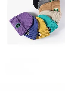 Disposizione piatta di berretti in maglia colorati con patch lettera C in otto colori