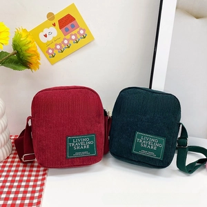 Detailed shot of retro red and dark green corduroy messenger bags with letter patches