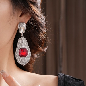 Elegant silver earrings with red gemstone and diamonds worn by a model in a close-up view