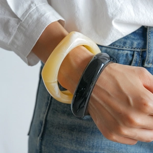 Minimalist geometric acrylic thick bangles in cream marble and black for a resort look