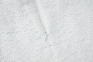Dettaglio macro del tessuto in pizzo bianco con chiusura a zip invisibile pulita