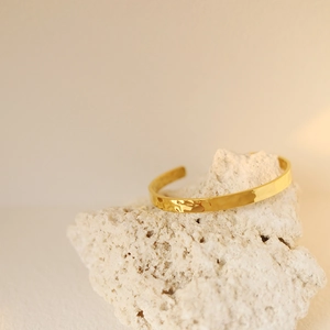 Macro view of gold plated stainless steel bracelet with irregular lunar hammer texture