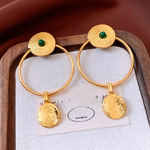Détail de boucles d'oreilles vintage en or avec pierre malachite verte et motif spirale