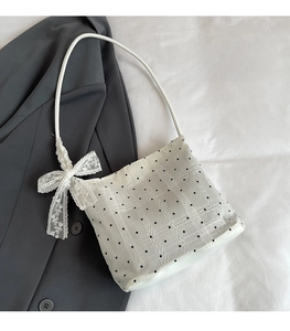 Detailed shot of white polka dot lace bucket bag featuring a decorative bow accent