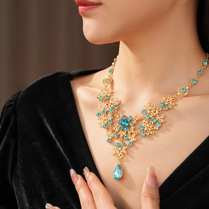Close-up of vintage golden necklace with blue crystals and leaf pattern on a model