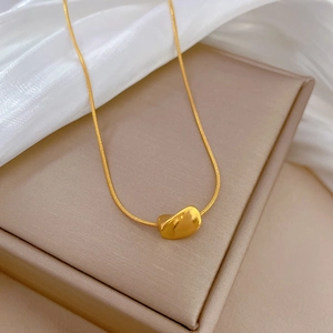 Detailed close-up of a gold-plated twisted bean pendant on a fine snake chain necklace