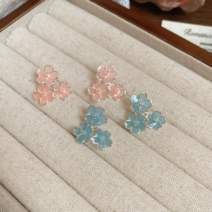 Détail de boucles d'oreilles fleurs en résine rose et bleue dans un coffret à bijoux