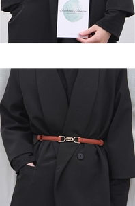 Detail of a brown slim leather belt with gold buckle on a black blazer jacket