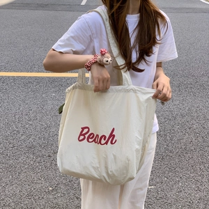 Close-up of beige cotton canvas tote bag featuring red printed Beach lettering design