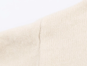 Gros plan sur la maille douce en laine blanc cassé et les coutures de haute qualité
