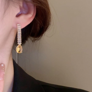 Gros plan d'un mannequin portant des boucles d'oreilles dorées avec gouttes jaunes