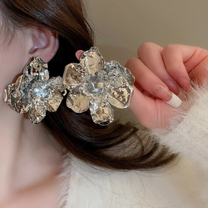 Detailed view of large silver metal flower earrings with 3D textured hammered petals