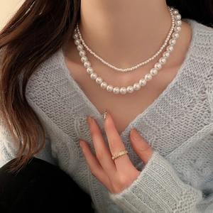 Gros plan d'un collier de perles à deux rangs et d'une bague dorée sur un mannequin