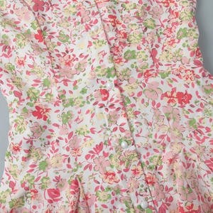 Detailed close-up of floral print fabric with white pearl buttons on a summer mini dress