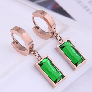 Macro detail of rose gold hoop earrings with emerald green rectangular gemstones