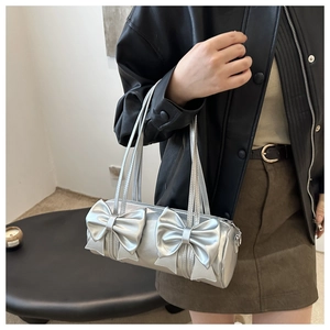 Detail of silver metallic cylinder bag featuring decorative 3D double bow accents