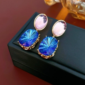 Macro detail of vintage gold earrings with pink round and blue oval crystal stones