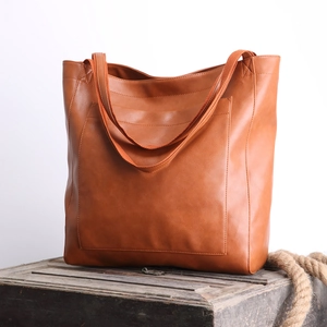 Détail du cabas vintage en cuir ciré marron avec poche frontale et texture lisse