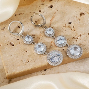 Elegant silver geometric drop earrings with triple white zircon stones on silk fabric