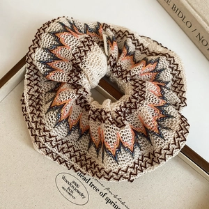 Détail d'un chouchou en tulle bohème avec broderie colorée dans une boîte en bois