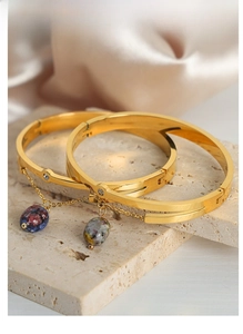 Detailed shot of gold plated steel bangles with natural stone pendants and zircon inlay