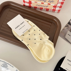 Chaussettes courtes en coton à pois jaunes présentées dans un plateau en bois rustique