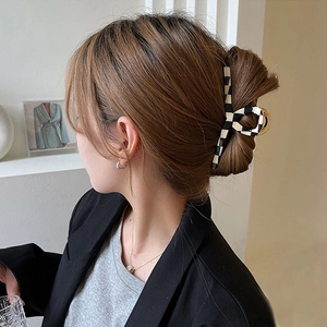 Large checkerboard acetate hair claw clip shown in a natural side-back hairstyle view
