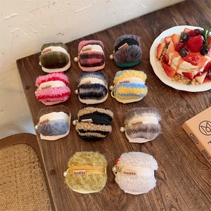 Detail showing macaron-shaped plush cases in various colors on a rustic wooden table