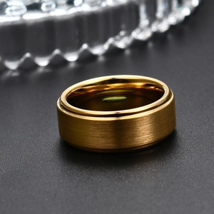 Primer plano de anillo ancho dorado en acero con acabado cepillado y bordes pulidos