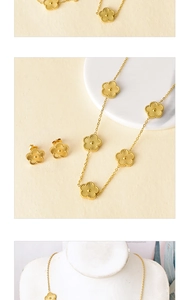 Macro detail of golden five-petal flower necklace and matching earrings on marble stand