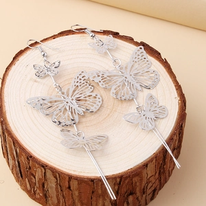 Long layered cutout butterfly drop earrings in silver finish on a rustic wood base