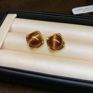 Close-up of vintage gold oval earrings with amber tiger eye stone on silk lining