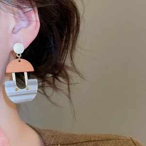 Detailed view of U-shaped marble resin earrings with gold studs worn by a model