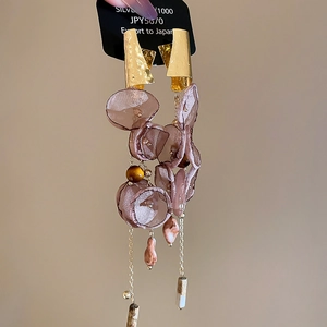 Detail of floral tassel earrings with pink organza petals and golden metal accents