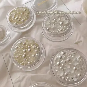 Pearlescent white mixed size mermaid nail art pearls in a clear round jar on silk