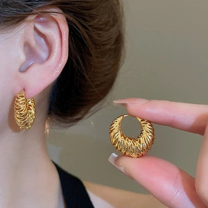 Détail de la boucle d'oreille créole plaquée or 18 carats avec texture tressée creuse