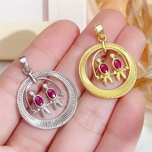 Detailed view of handmade bird pendants with red gemstones in gold and silver finish