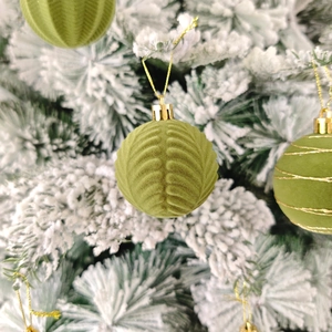 Gros plan de boules de Noël vertes floquées avec texture de feuilles et lignes dorées