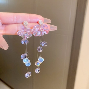 Detail of purple chiffon petal earrings with clear beaded tassels held by a hand