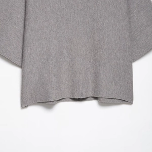 Gros plan de l'ourlet en maille grise montrant la texture douce et la coupe ample