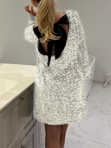 Dettaglio mini abito di paillettes con grande fiocco nero e design con schiena scoperta