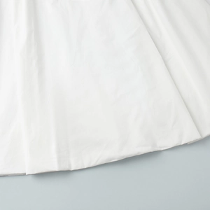 Gros plan du tissu en coton blanc pur montrant la texture douce et les détails de l'ourlet