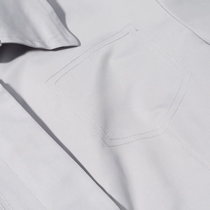 Detailed close-up of a light gray blazer chest pocket with precise stitching and fabric texture